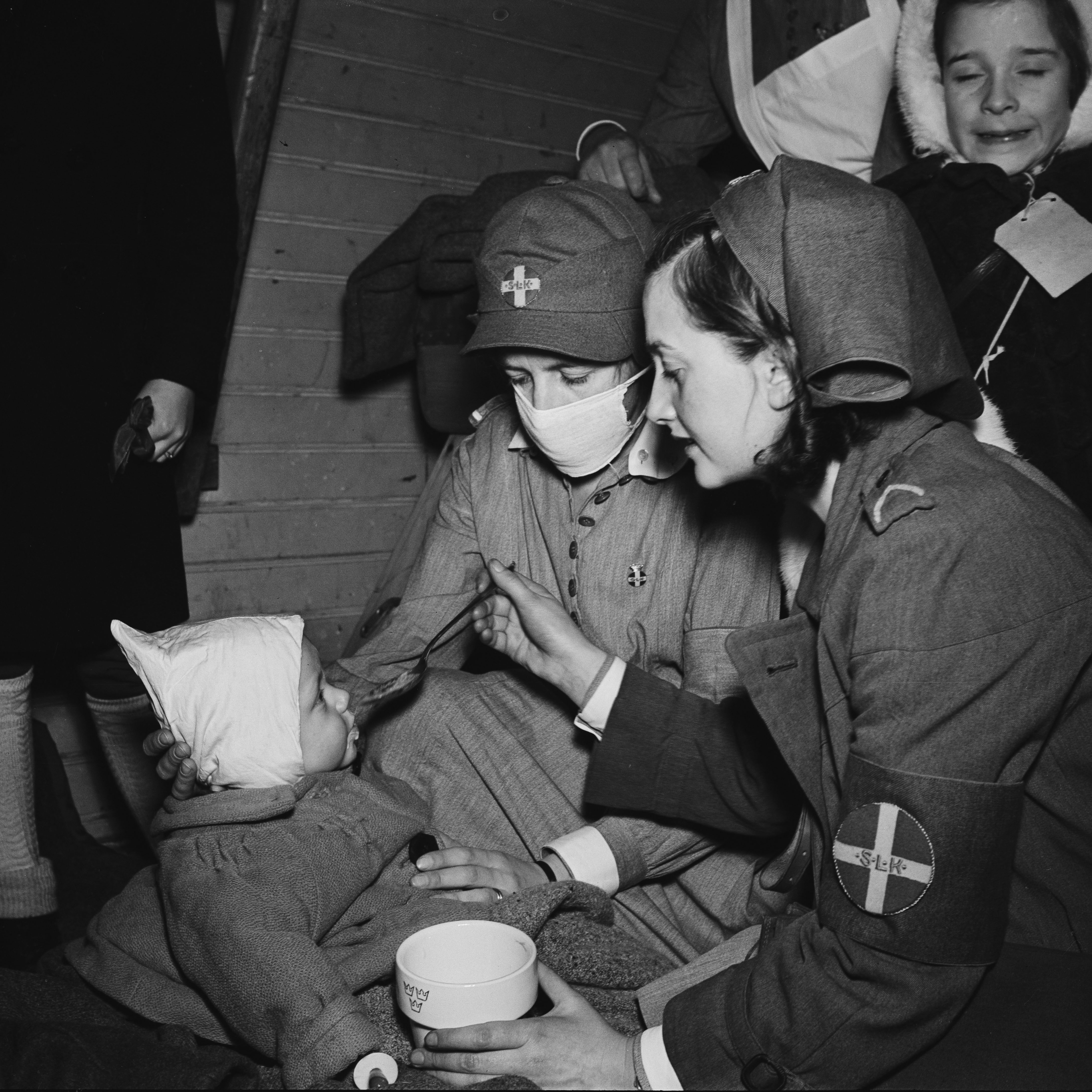 Två lottor som matar ett litet barn.