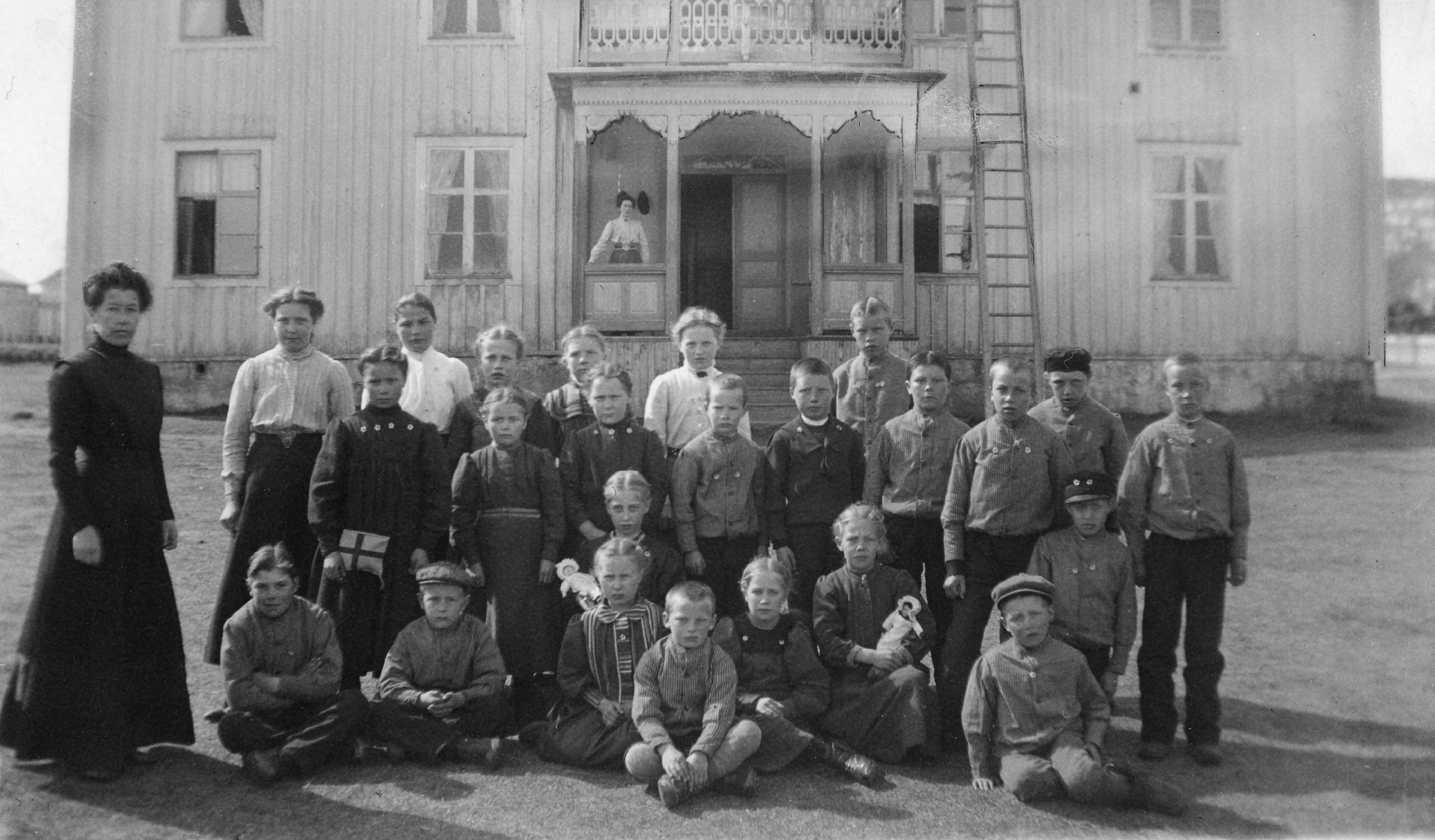 Barn och skolfröken utanför arbetsstugan i Arvidsjaur 1910.