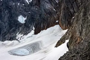 Smältande glaciär vid en brant bergsvägg.