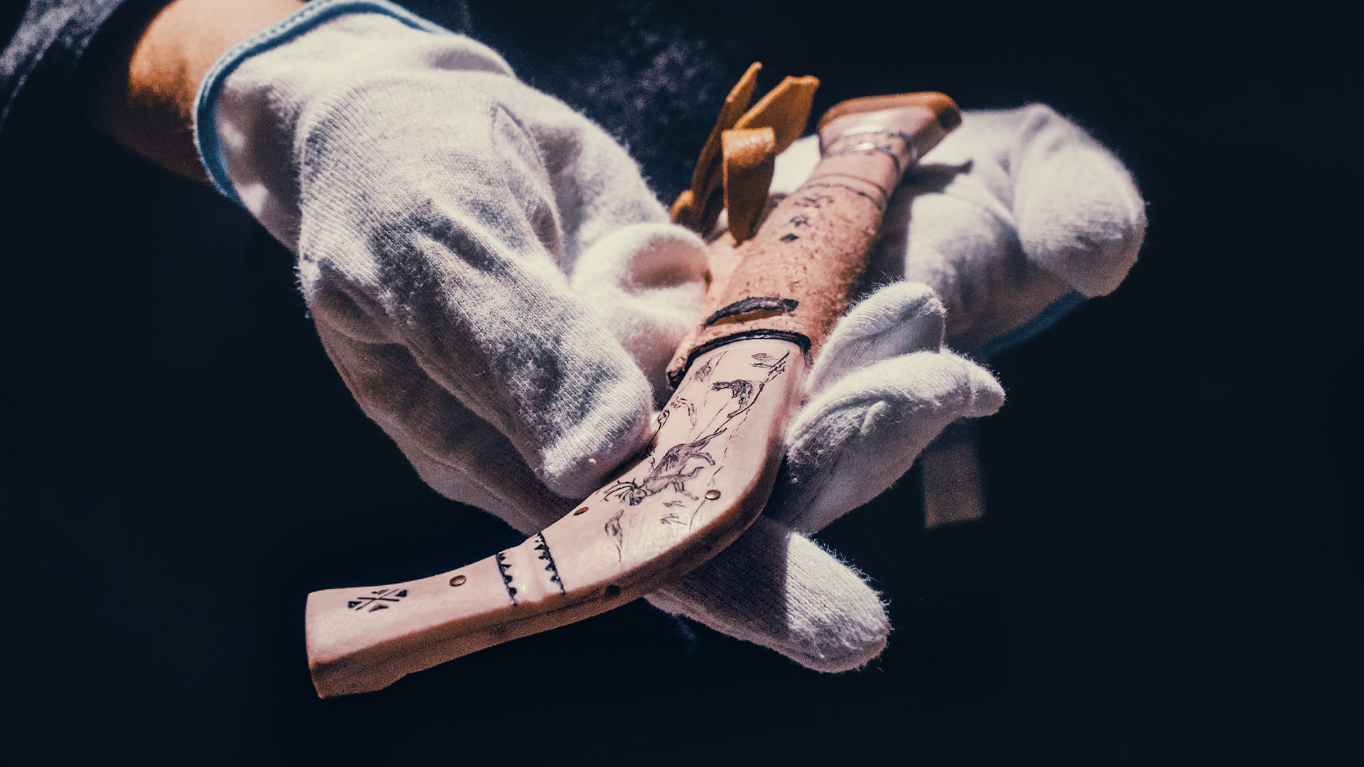 Händer som håller i en kniv med samiska motiv.