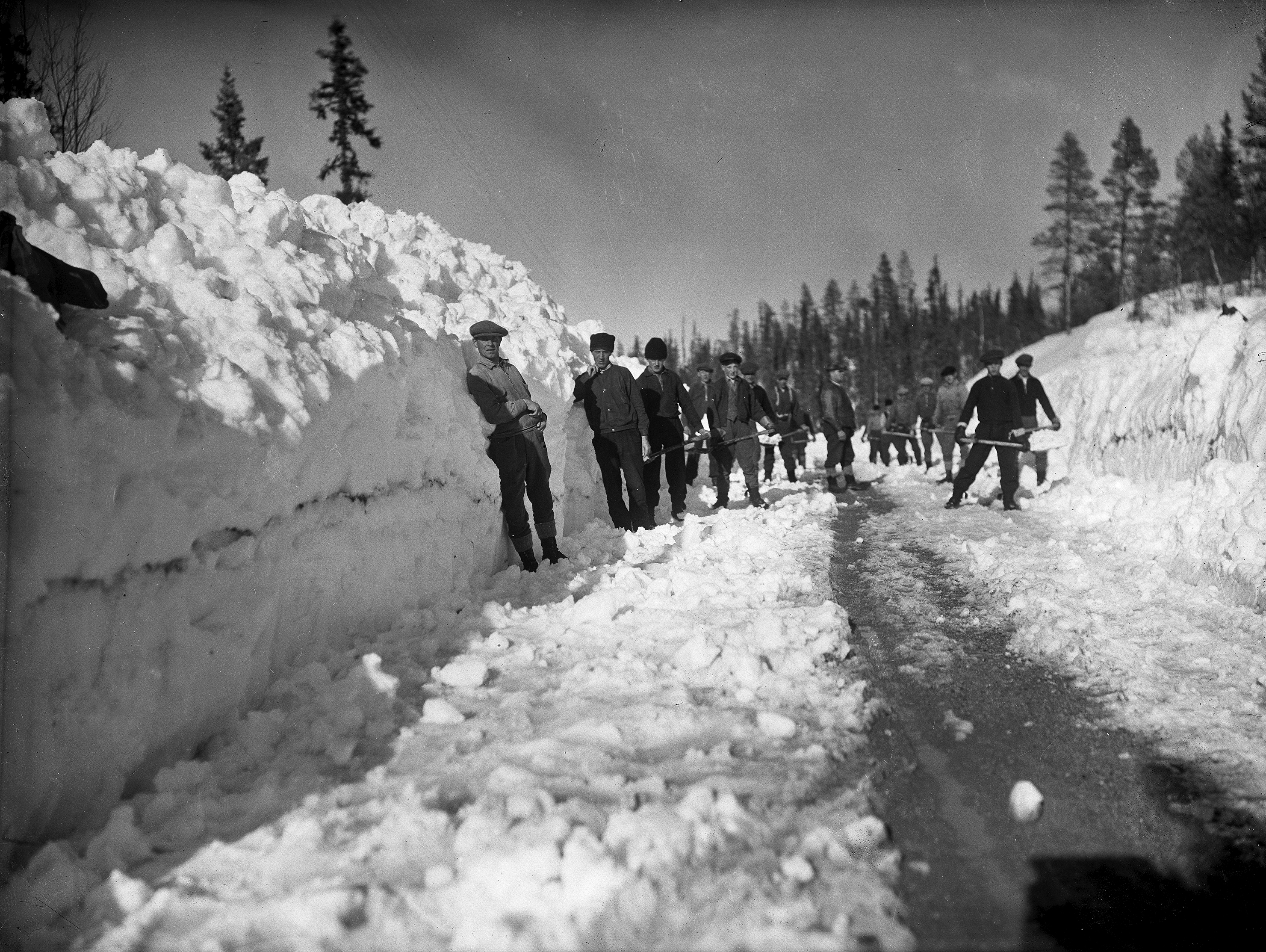 'Äldre bild av pojkar som snöröjer en väg för hand i Malmberget.'