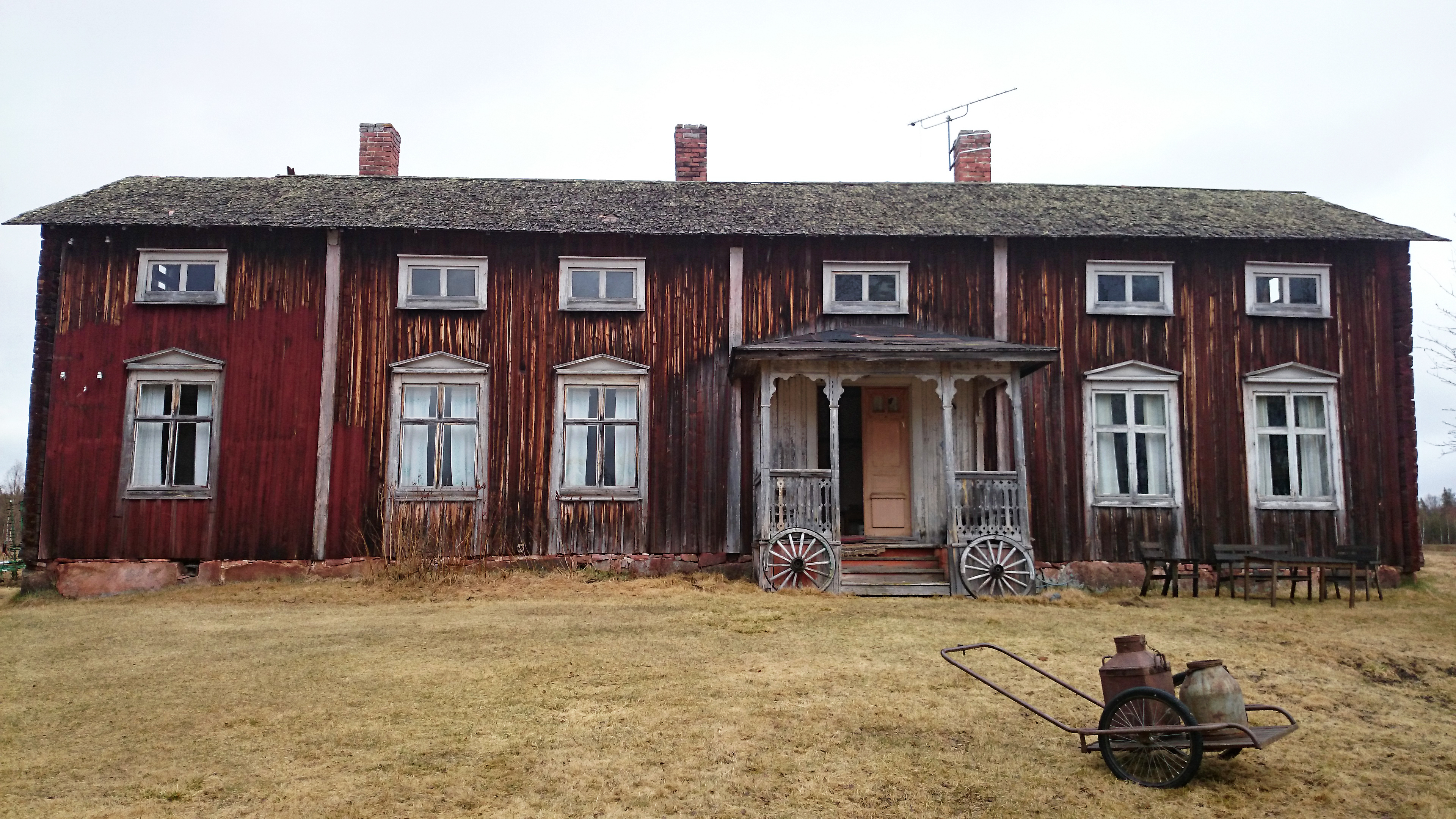 'Gammal Norrbottensgård som förfallit. Framför gårdens tår en mjölkkärra.'